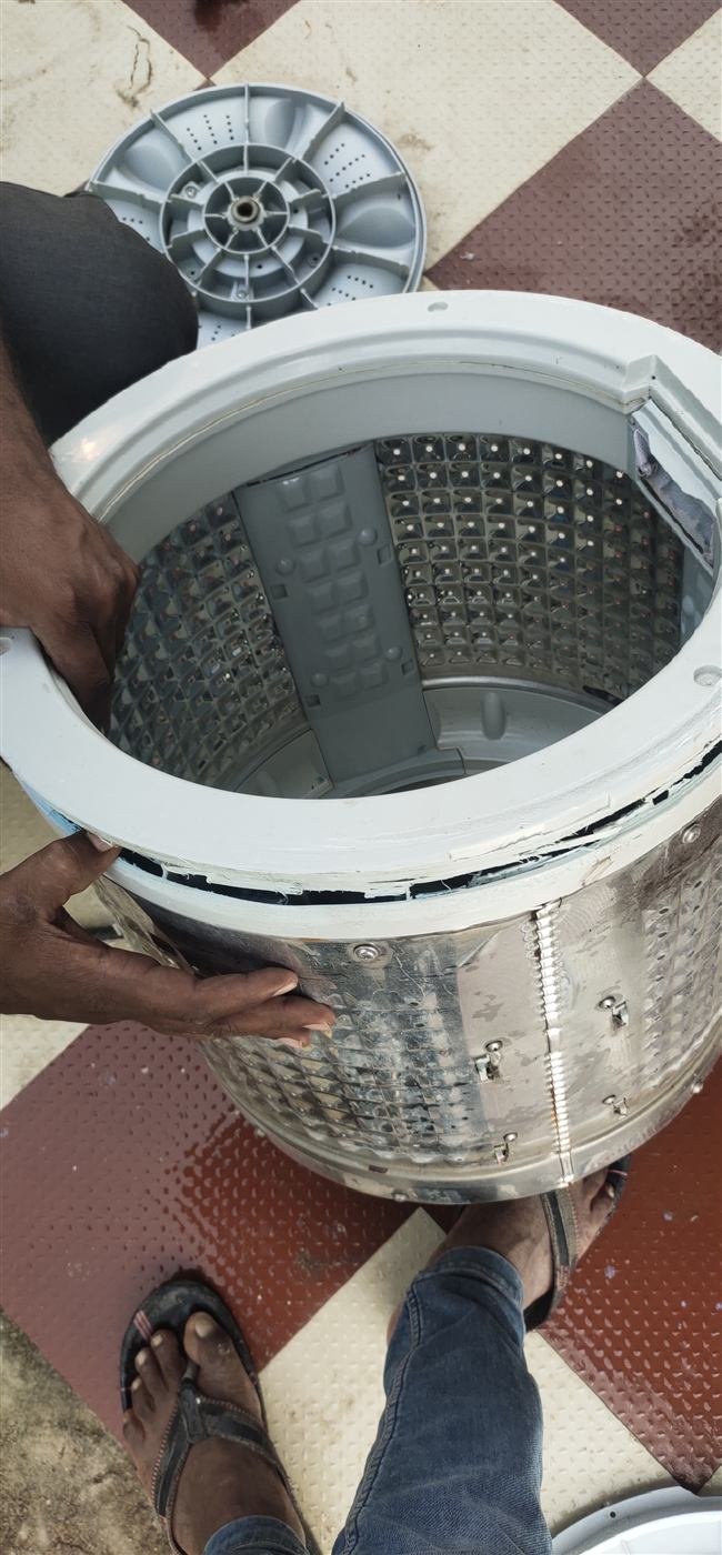 AN Repair Services technician holding a washing machine drum during a repair in Kamareddy